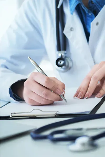 Advanced-Diagnostic-Testing-Treatment Close up of a doctor in a white coat, writing on a notepad, representing functional medicine testing offered by Marina Fay, PA-C in Aventura-North Miami.