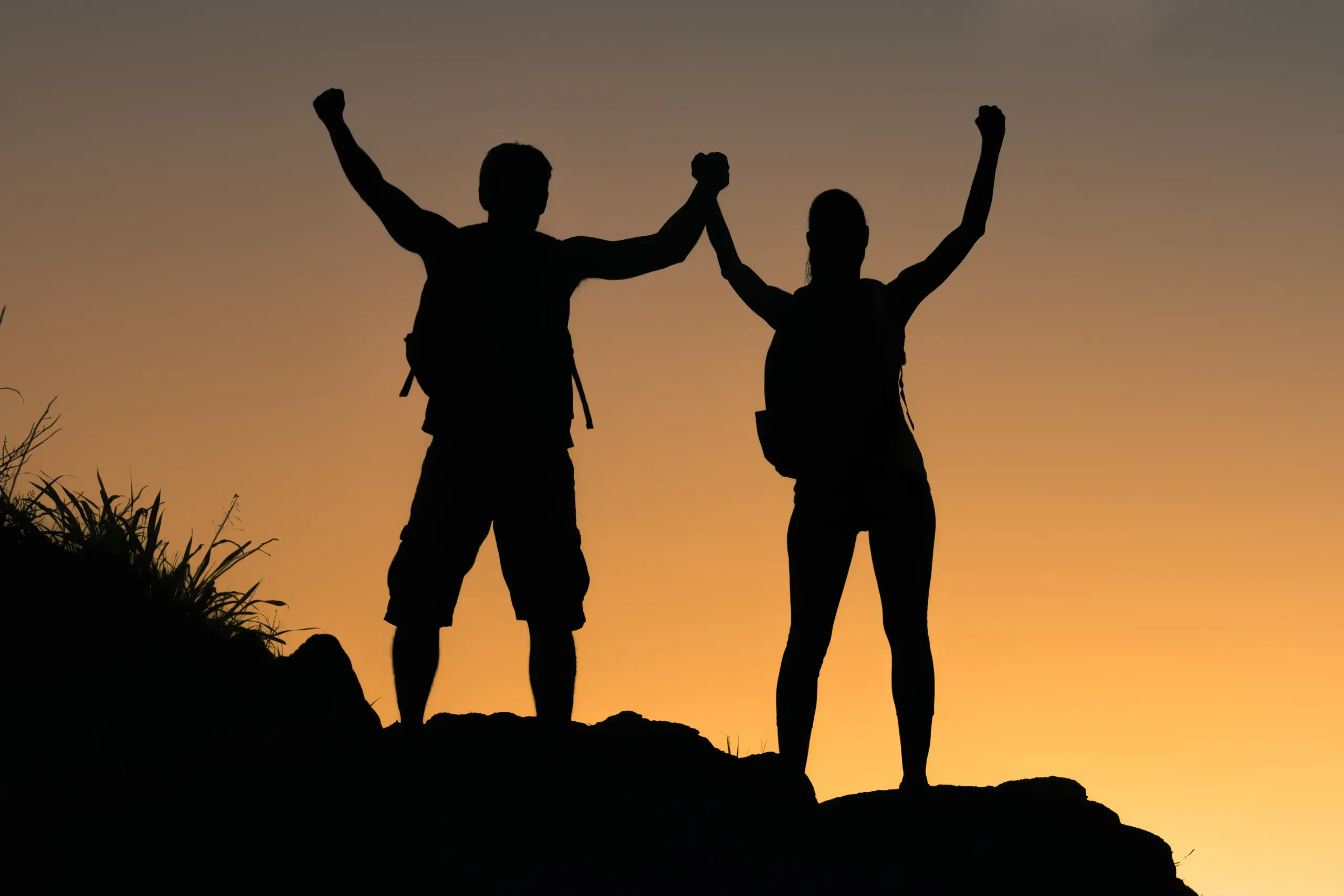 Amino-Blend-IV-Therapy-Clinic A hiker couple silhouette in the sunset, the couple is holding hands with arms up celebrating accomplishment. Schedule a consultation with Marina Fay, PA-C in Aventura-North Miami for an Amino Blend IV Therapy treatment.