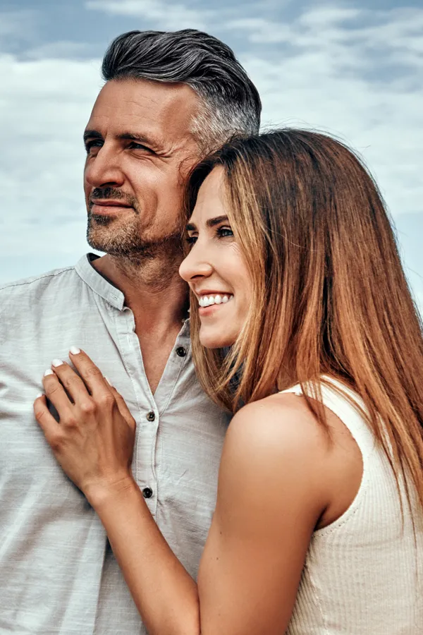 Anti-Aging-And-Longevity-Peptides-Treatment A middle-aged couple look out at the ocean. Get Anti-Aging And Longevity Peptide Treatment from Marina Fay, PA-C in Aventura-North Miami.