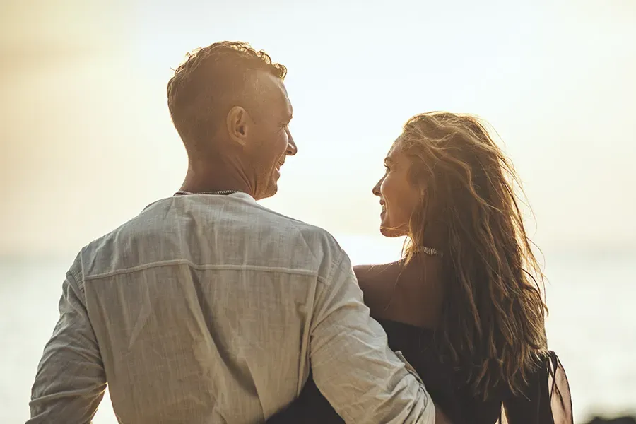 Anti-Aging-Clinic A couple gazes at each other on the beach at sunrise, viewed from behind. Schedule Anti-Aging treatment from Marina Fay, PA-C in Aventura-North Miami.