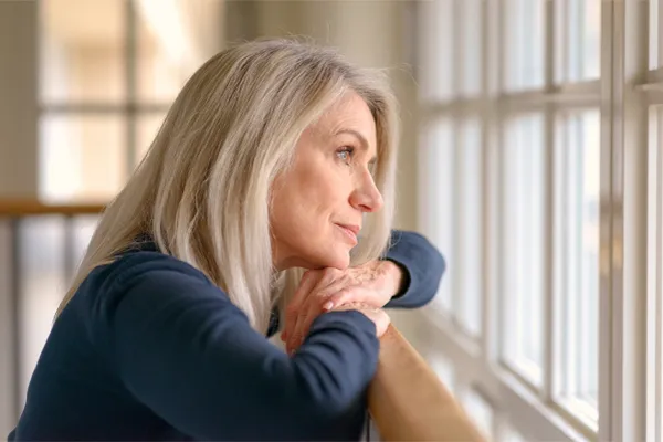 Brain-Fog-Clinic A thoughtful woman gazes out a window, symbolizing the mental fatigue and distraction often associated with brain fog. Get root-cause brain fog treatment by Marina Fay, PA-C in Aventura-North Miami.