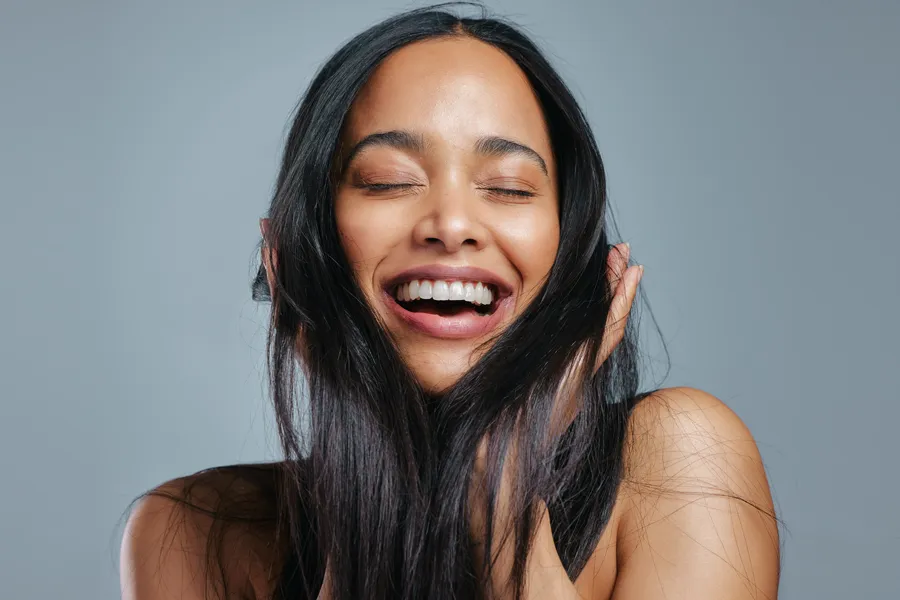 Exosomes-for-Hair-Restoration-Clinic A woman runs her fingers through her long, thick, lustrous hair. Get exosomes for hair restoration from Marina Fay, PA-C in Aventura-North Miami.