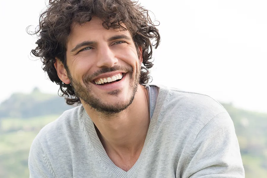 Hair-Restoration-Doctor A man with a full head of curly brown hair. Get hair restoration treatments from Marina Fay, PA-C in Aventura-North Miami.