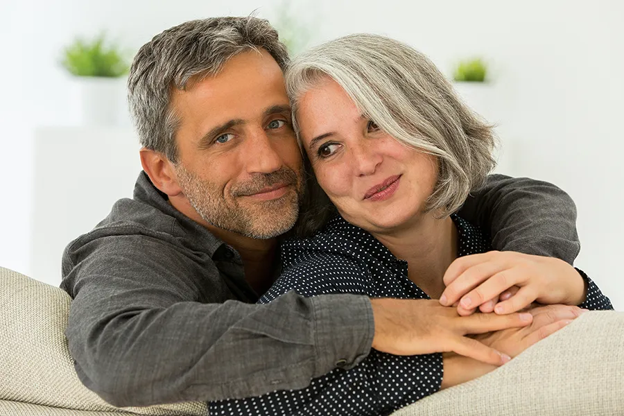 Hormonal-and-Vitality-Peptides-Clinic A middle-aged couple holding each other on the couch. Get Hormonal and Vitality Peptide Treatment from Marina Fay, PA-C in Aventura-North Miami.
