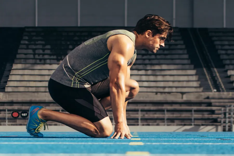Lean-Muscle-and-Recovery-Clinic A white man kneels at the starting line on a track, determined to do his best. Get treatment for lean muscle loss and recovery from Marina Fay, PA-C in Aventura-North Miami.