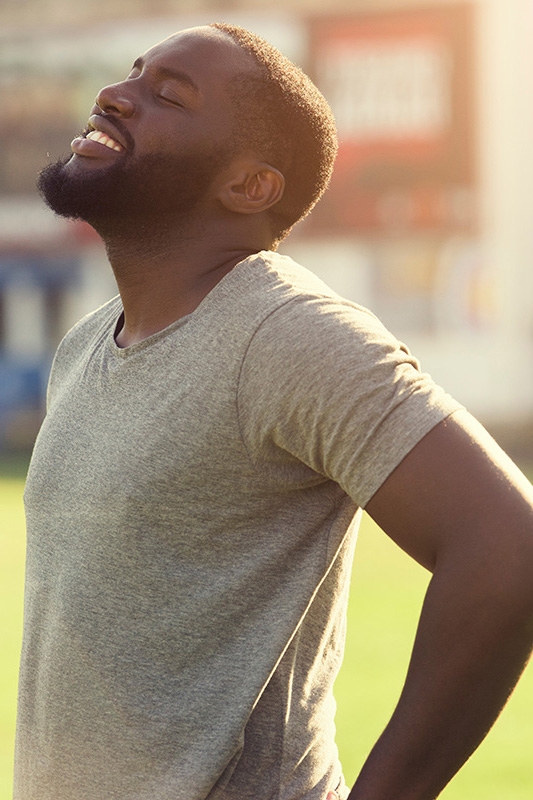 Lean-Muscle-and-Recovery-Treatment A black man in a gray t-shirt and smiles, looking up with closed eyes after a satisfying workout. Get treatment for lean muscle loss and recovery from Marina Fay, PA-C in Aventura-North Miami.