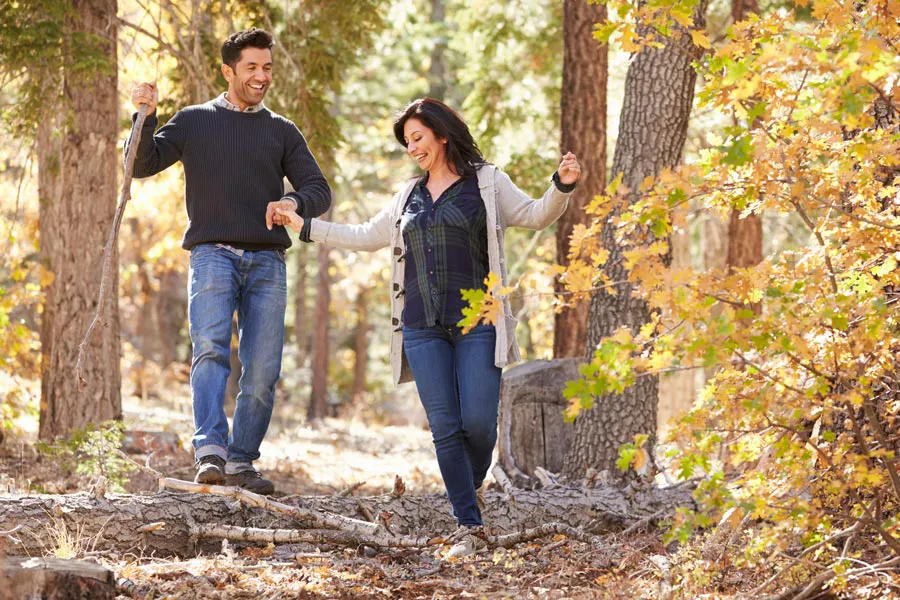 Lyme-Disease-Clinic A couple happily hiking in the forest in fall. Get treatment for Lyme Disease from Marina Fay, PA-C in Aventura-North Miami.