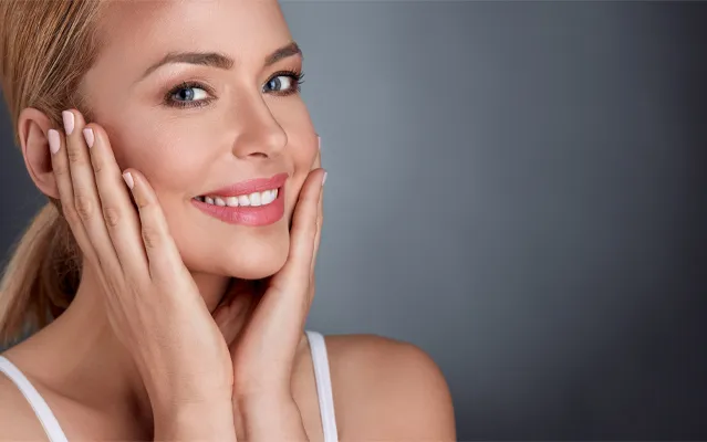 Matrixyl-Peptide-Therapy-Clinic A beautiful blonde woman holds her cheeks in her hands. Get Matrixyl peptide therapy from Marina Fay, PA-C in Aventura-North Miami.