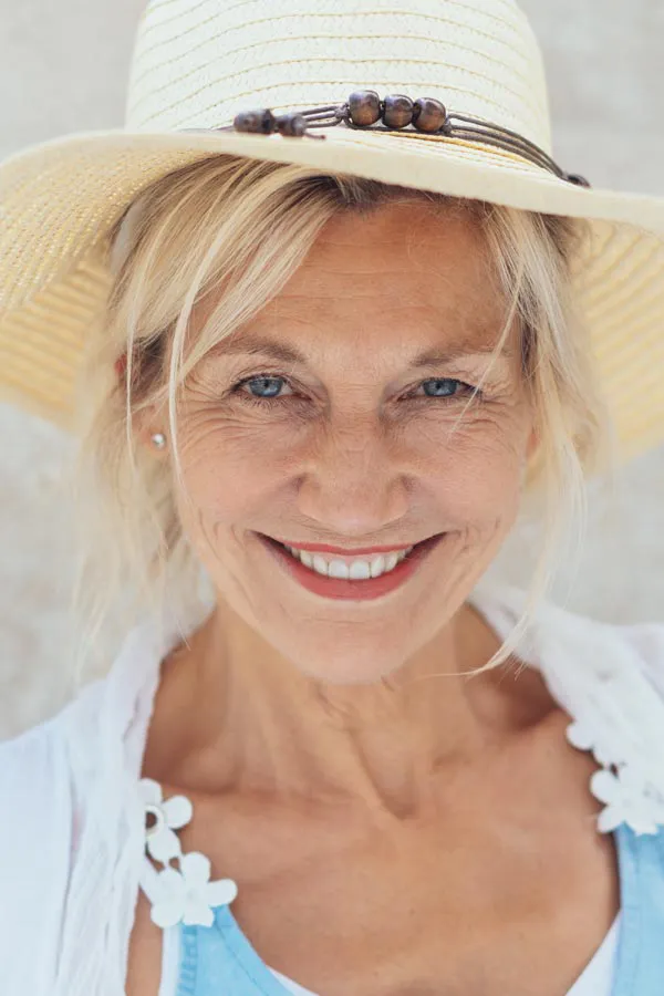 Menopause-Treatment A beautiful, smiling older woman with blonde hair and a sunhat, happy with menopause treatment from Marina Fay, PA-C in Aventura-North Miami.
