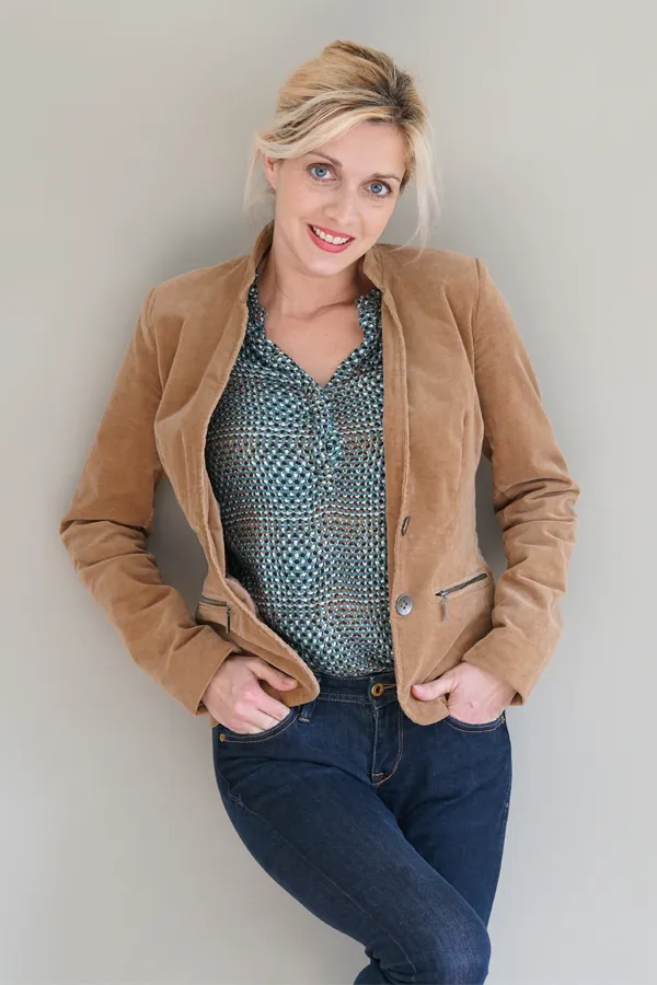 Metabolic-Syndrome-Treatment A smiling blonde woman in a tan leather jacket leans against a gray wall. Schedule metabolic syndrome from Marina Fay, PA-C in Aventura-North Miami.