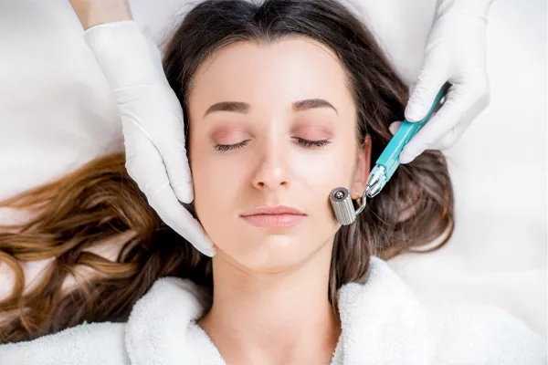Microneedling-Doctor A woman in a white robe closes her eyes and receives a microneedling procedure from Marina Fay, PA-C in Aventura-North Miami.