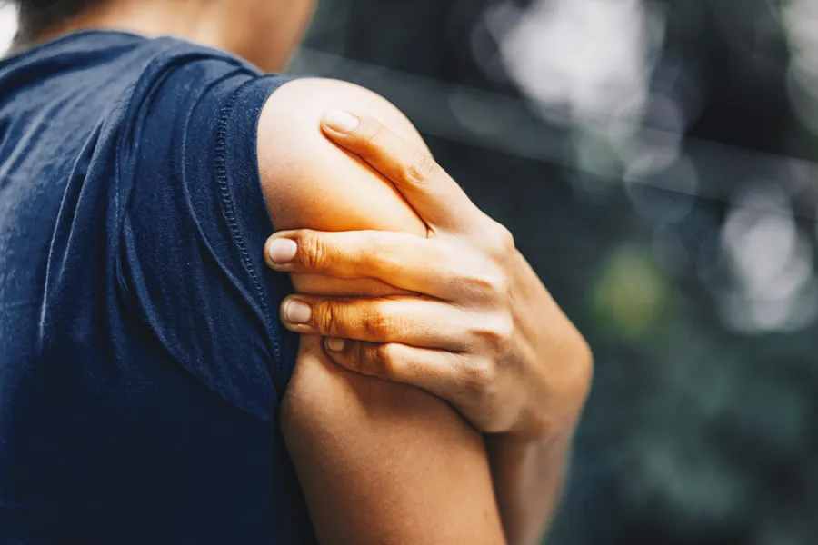 PRP-for-Shoulder-Injury-Doctor Close up of a woman in a tank top holding her shoulder in pain, which can be relieved by PRP treatment for shoulder pain from Marina Fay, PA-C in Aventura-North Miami.