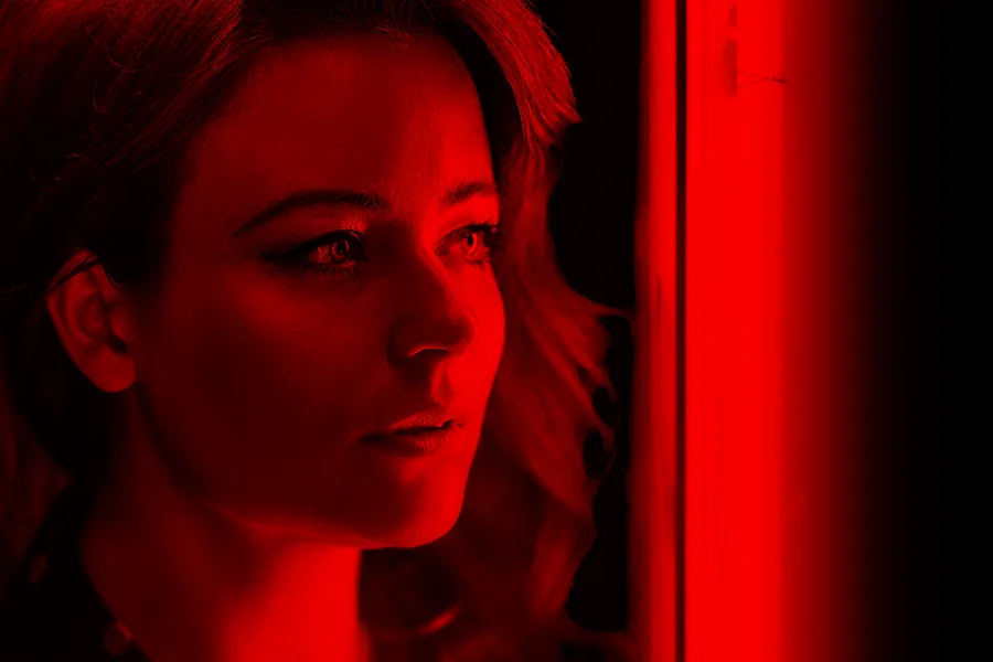 Red-Light-Therapy-for-Hair-Restoration-Clinic A woman with full long hair in red light. Get Red Light Therapy for Hair Restoration from Marina Fay, PA-C in Aventura-North Miami.