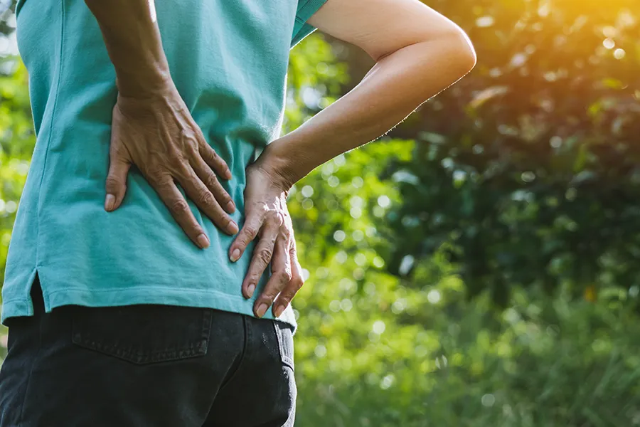 Regenerative-Medicine-for-Back-Pain-Clinic A woman holds her lower back in pain. Schedule Regenerative Medicine for Back Pain from Marina Fay, PA-C in Aventura-North Miami.