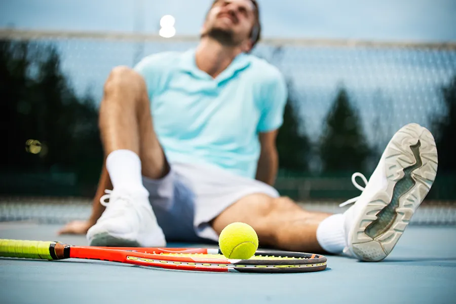 Regenerative-Medicine-for-Injury-Rehabilitation-Clinic A man sitting on a tennis court with an injury. Schedule Regenerative Medicine for Injury Rehabilitation from Marina Fay, PA-C in Aventura-North Miami.