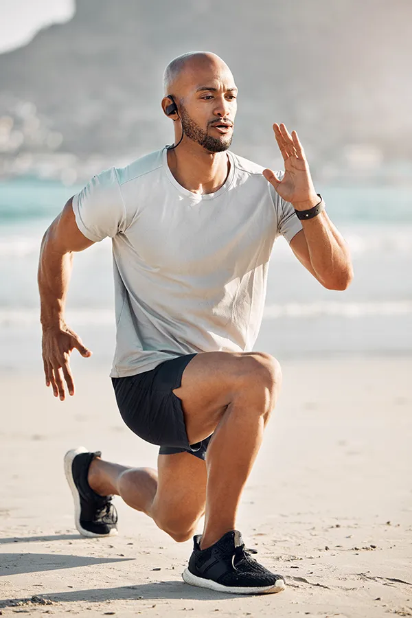 A man does lunges on the beach. A man sitting on a tennis court with an injury. Get Regenerative Medicine for Sore Muscles from Marina Fay, PA-C in Aventura-North Miami.