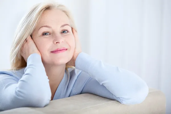 Stem-Cell-Facial-Clinic A beautiful middle-aged blonde woman rests her head in her hands. Schedule stem cell facial treatment from Marina Fay, PA-C in Aventura-North Miami.