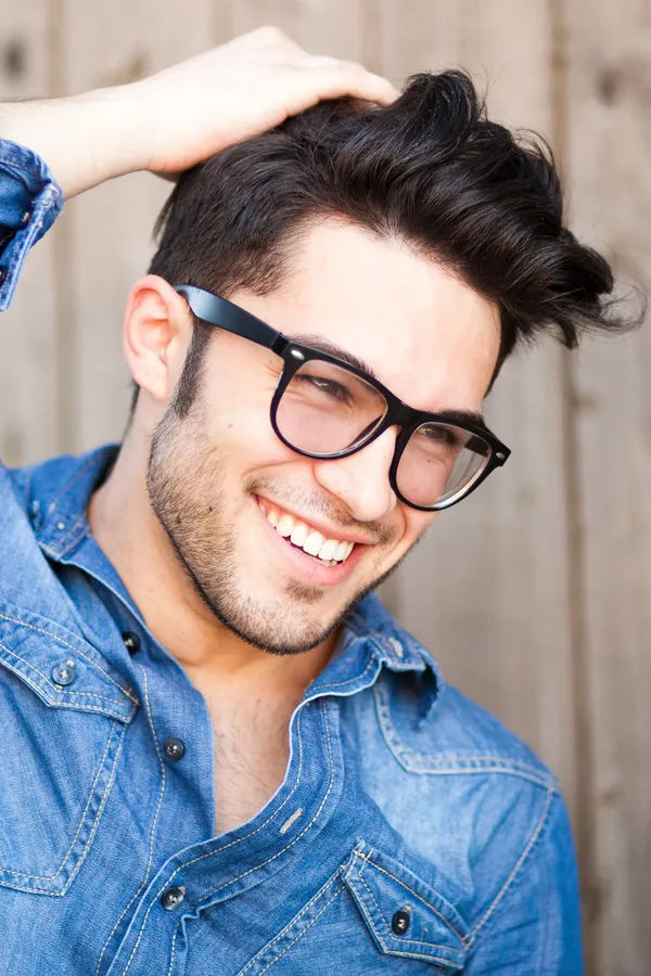 Stem-Cell-Hair-Restoration-Treatment A man with thick brown hair and glasses in a denim shirt. Get Stem Cell Hair Restoration Therapy from Marina Fay, PA-C in Aventura-North Miami.