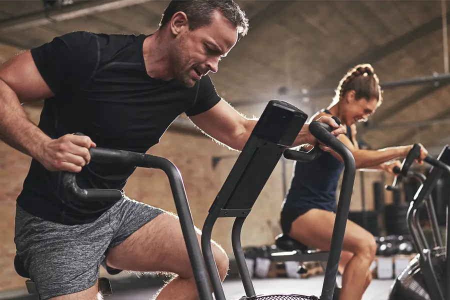 Tirzepatide-Doctor A couple in a brick gym work as hard as they can on exercise bikes, inspired by successful Tirzepatide treatment from Marina Fay, PA-C in Aventura-North Miami.